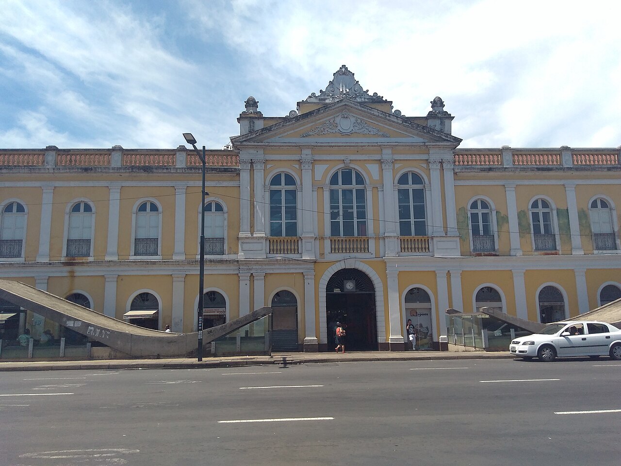 Fachada amarela e branca do Mercado Público de Porto Alegre, com dois pavimentos, janelas em arco e entrada central.