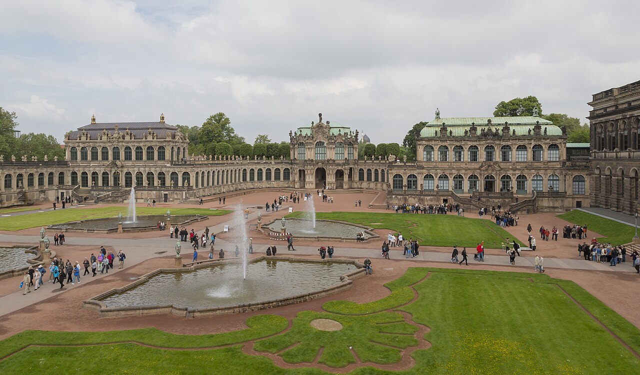 Pátio do Zwinger com canteiros ornamentais, espelhos d’água, fontes e edifícios barrocos com arcadas.