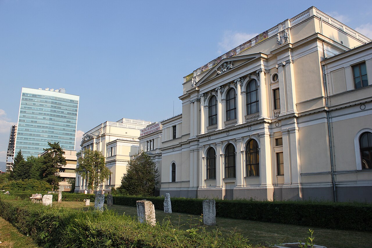 Fachada clara do Museu Nacional, com colunas, frontões, jardim e uma faixa em inglês informando fechamento no registro de arquivo.