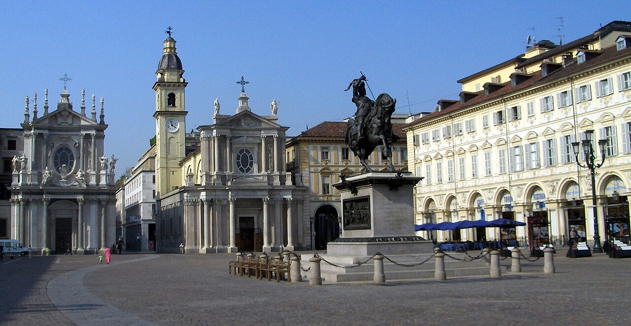Piazza San Carlo com estátua equestre sobre pedestal, duas fachadas de igrejas e edifícios com arcadas.
