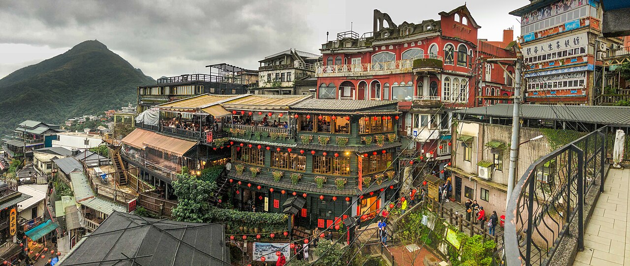 Encosta de Jiufen com escadarias e construções, incluindo a Amei Teahouse com varandas e lanternas vermelhas.
