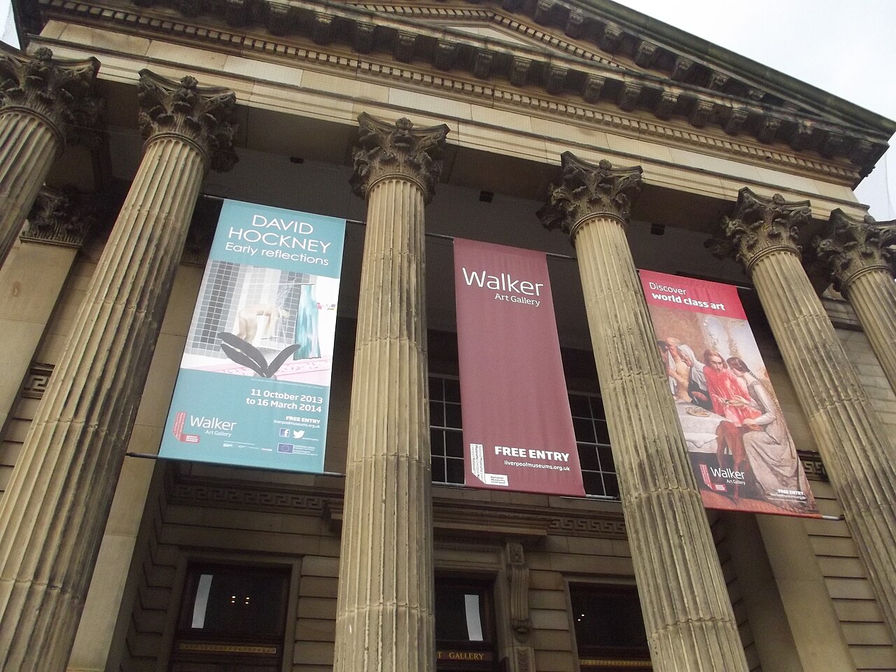 Fachada da Walker Art Gallery vista de baixo, com colunas ornamentadas e faixas de uma exposição de David Hockney anunciada para 2013 e 2014.