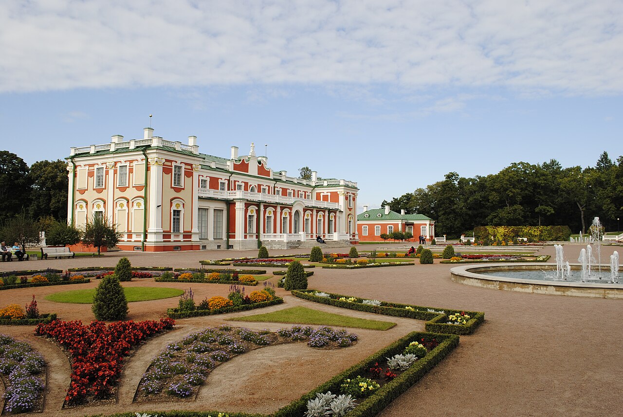 Palácio Kadriorg com fachada salmão e ornamentos brancos, telhados verdes e jardim geométrico com fonte à direita.