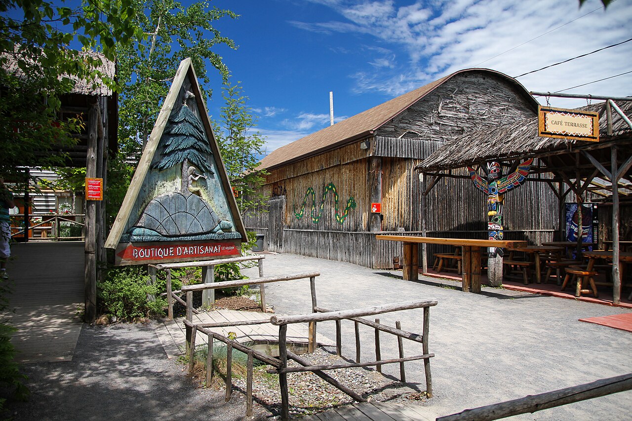 Construções de madeira e caminhos de cascalho no Onhoüa Chetek8e, com passarelas rústicas, placa de artesanato e mesas sob uma placa de Café Terrasse.