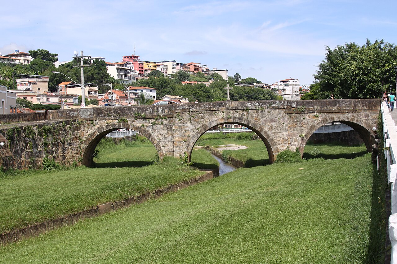 Ponte do Rosário em pedra, com três arcos visíveis e uma cruz sobre o parapeito, atravessando um curso d’água.